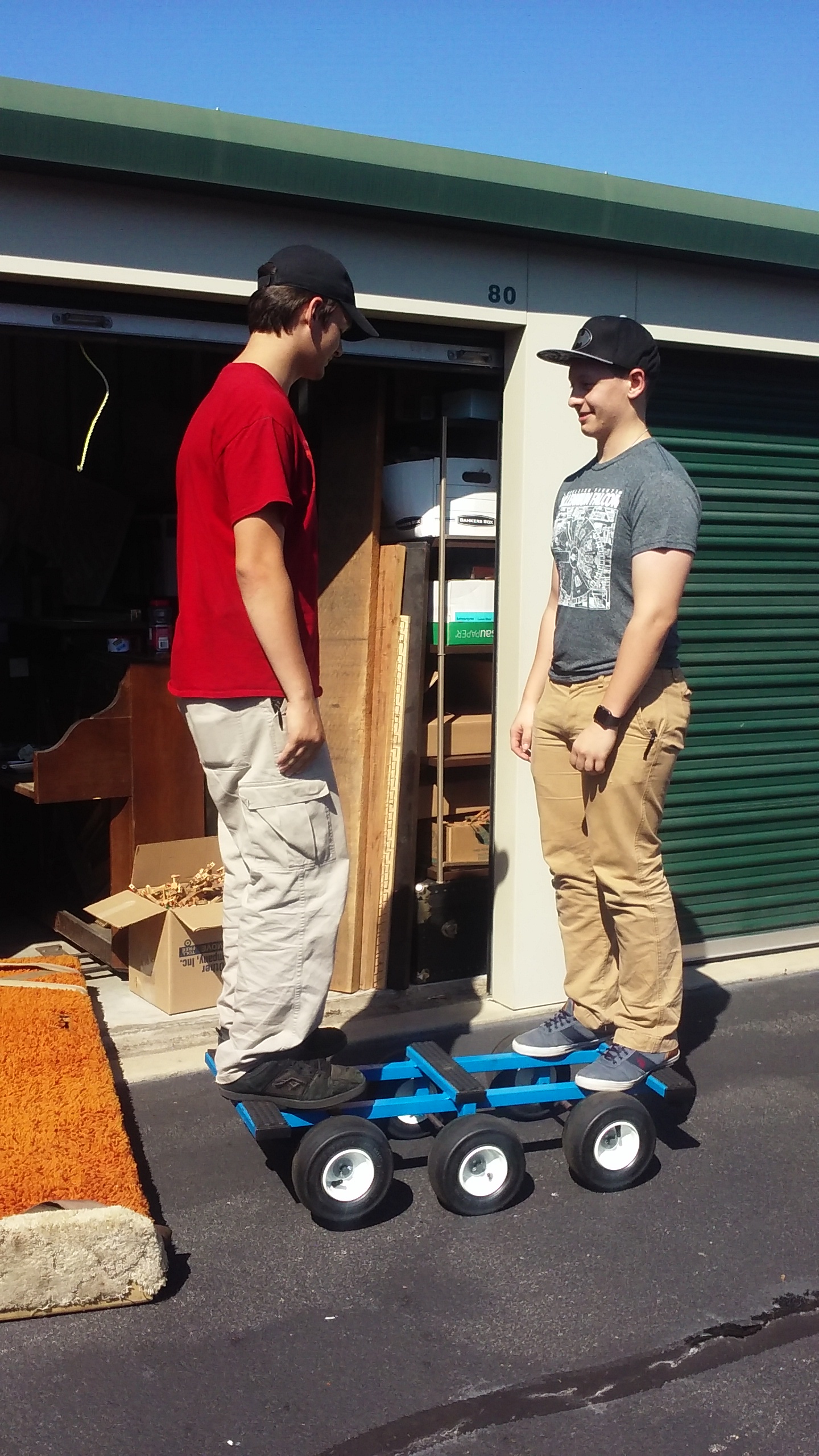 two young men standing on a piano dolly